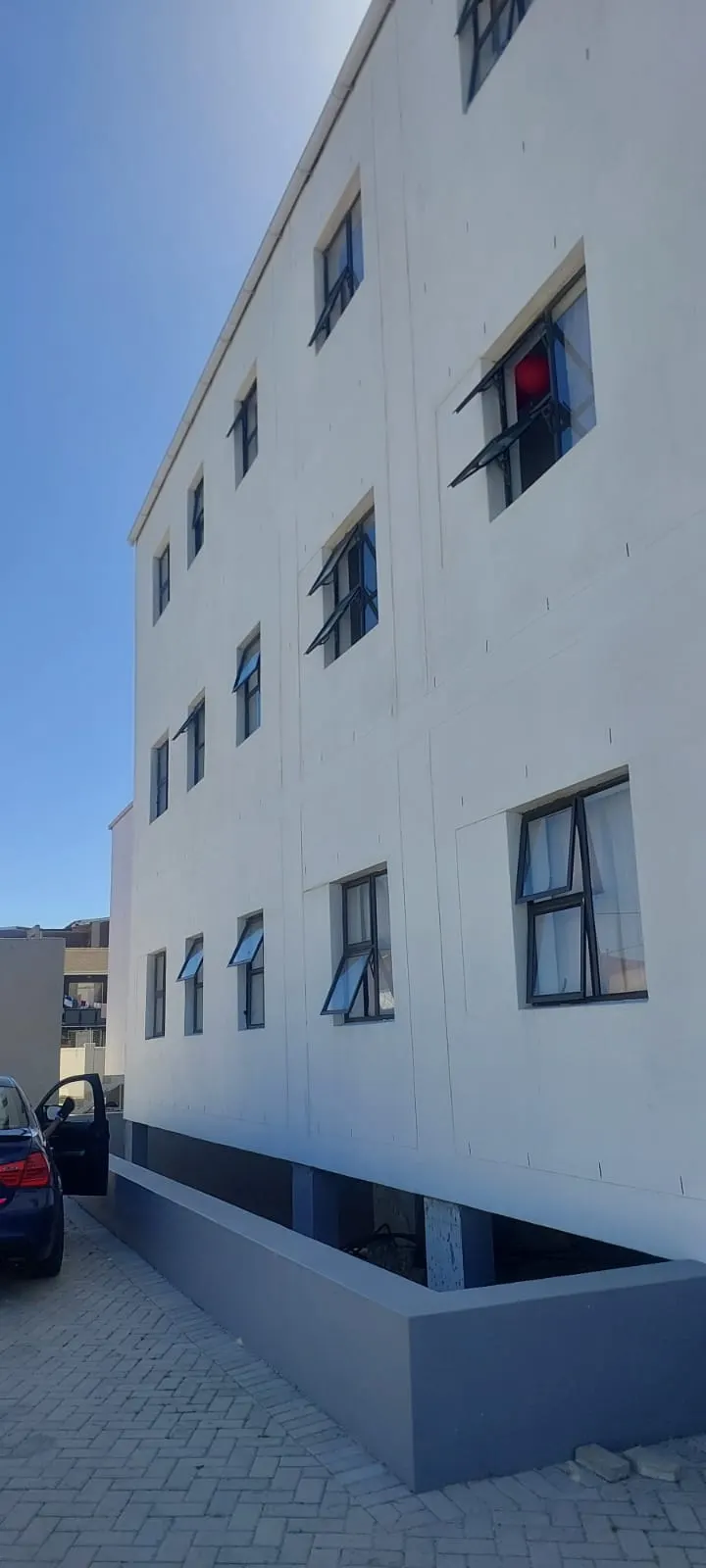 Three storey apartment block exterior painted white and grey