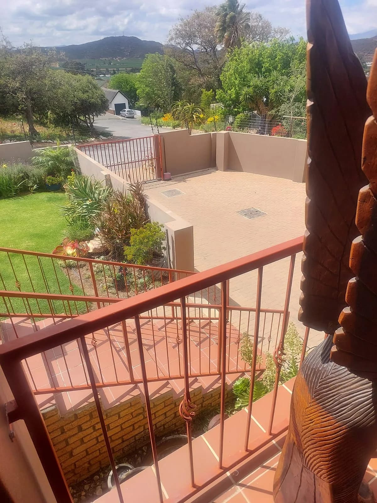 Painted balcony railing overlooking a garden and patio