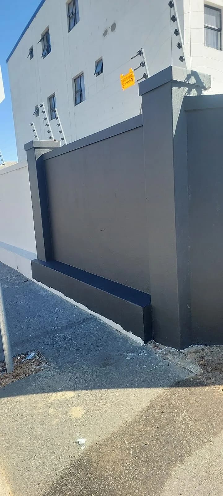Boundary wall painted charcoal with grey pillars