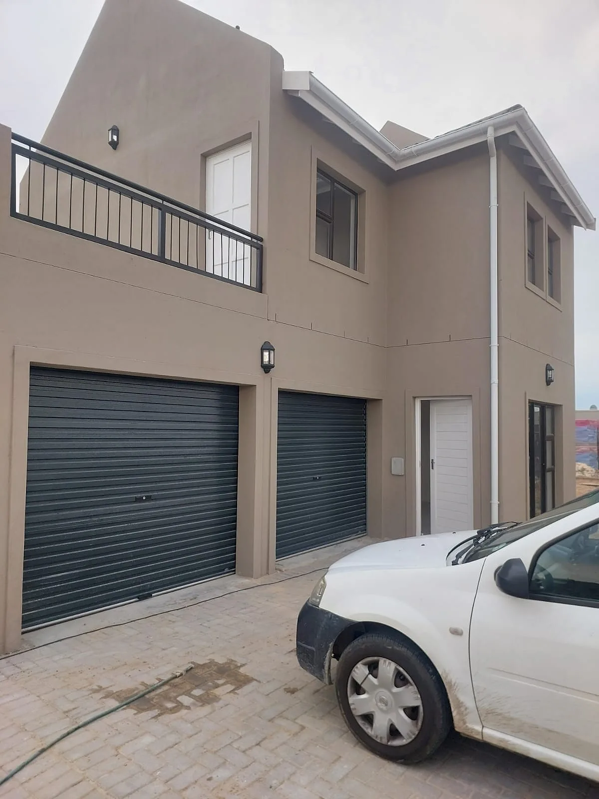 Double storey townhouse painted in a warm taupe with roller garage doors