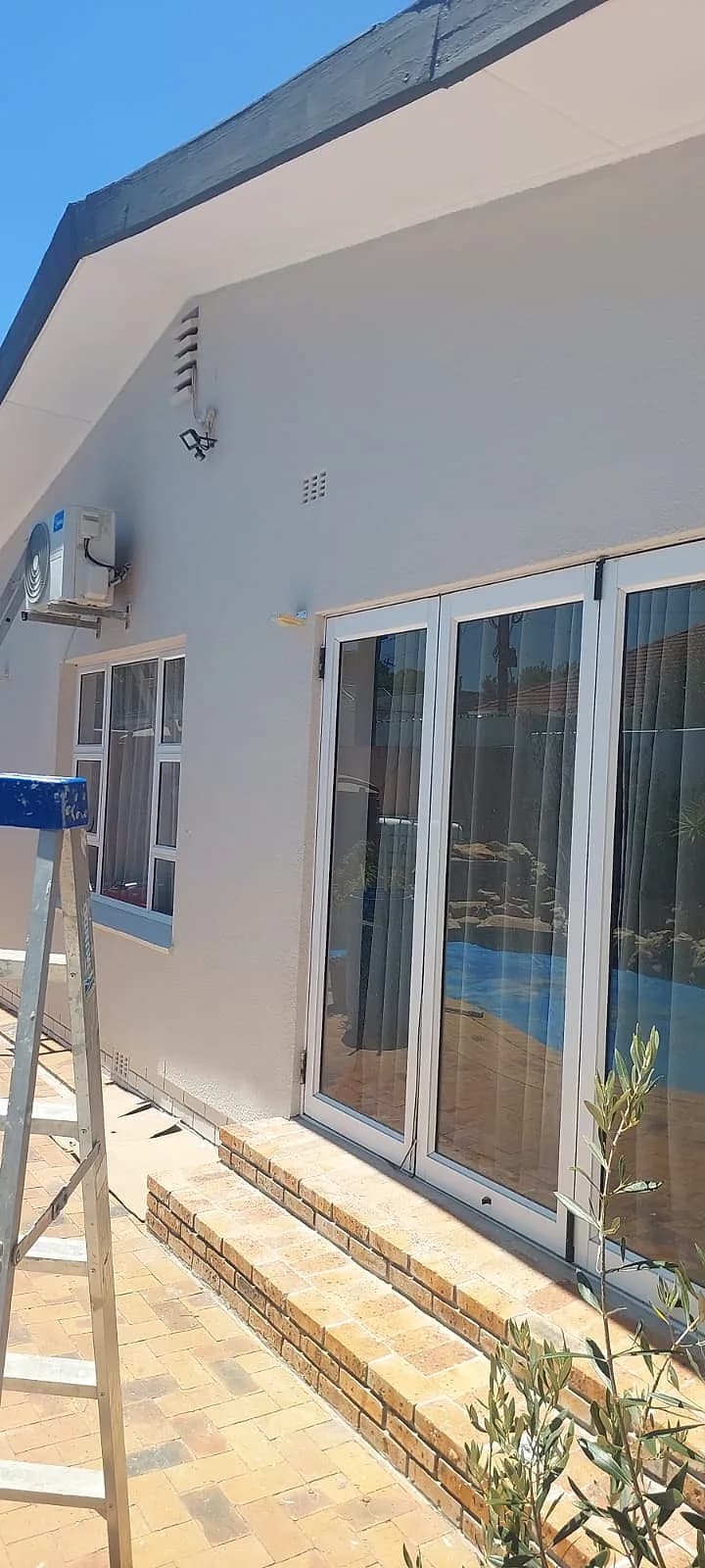 Exterior wall repaint around bifold doors, ladder in place