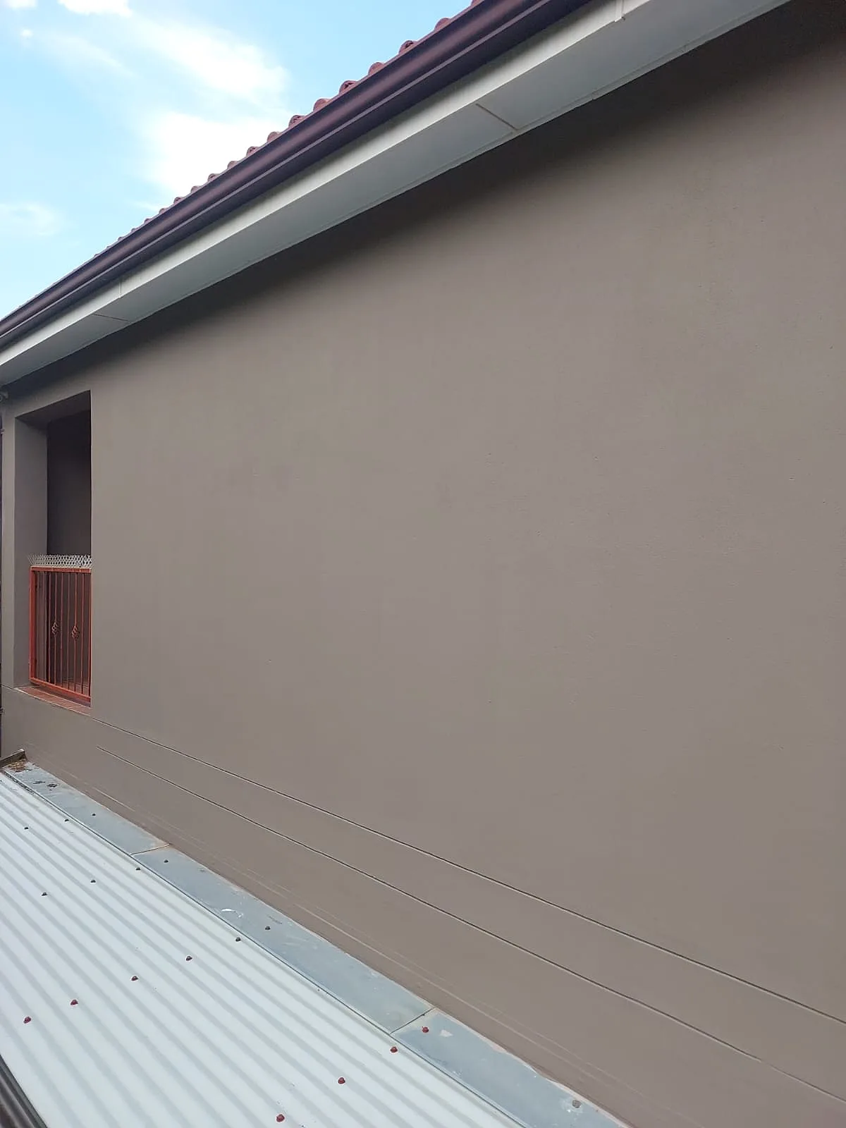 Smooth taupe exterior wall finish under a new fascia