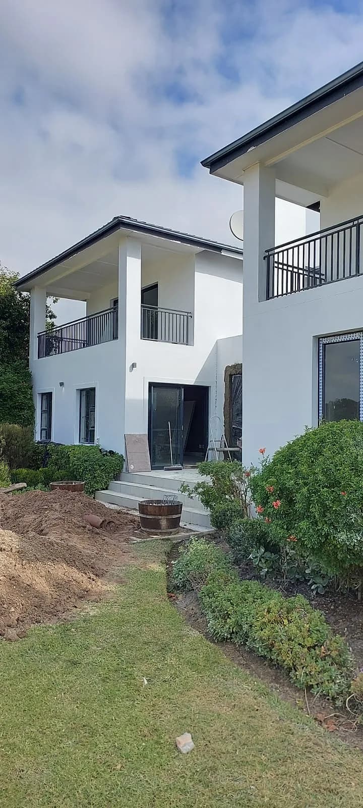 White painted home with balconies and a landscaped garden